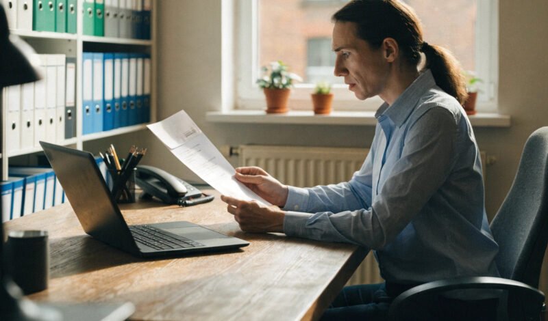 a gp practice manager reviewing an official contract notice at their desk