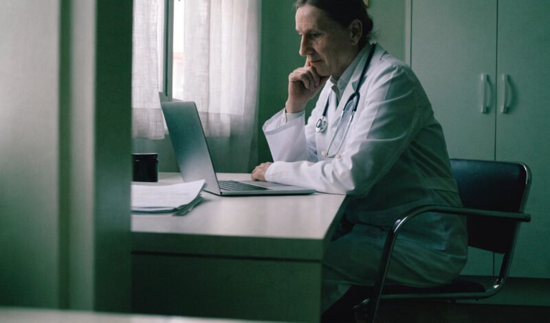 a gp working at a desk in a consultation room