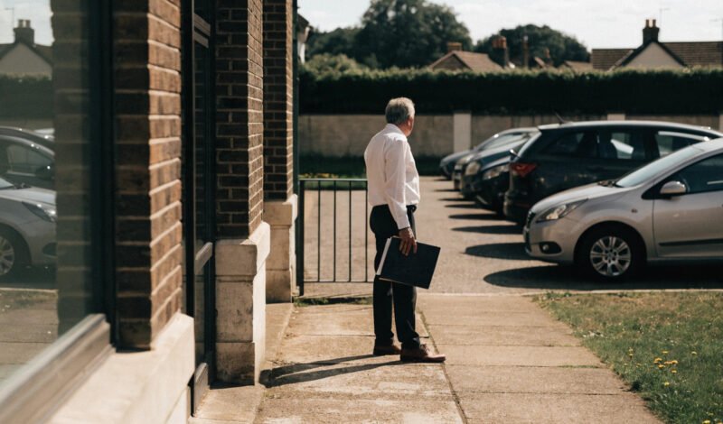 a retiring gp partner outside a surgery building considering options for their share in the premises