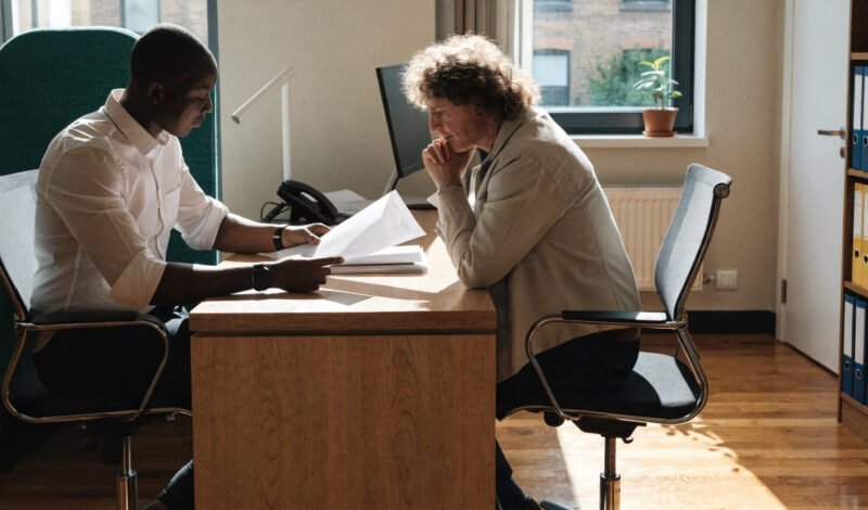 gp practice manager and partner reviewing an nhs gp contract in a surgery office