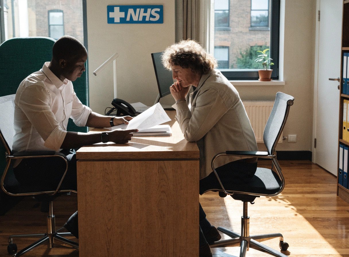 gp practice manager and partner reviewing an nhs gp contract in a surgery office