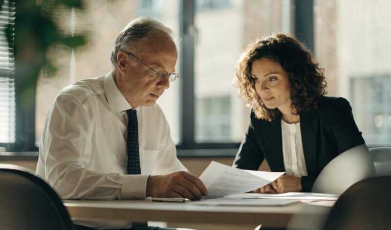 senior gp partner reviewing a partnership deed with a solicitor during a retirement age discussion