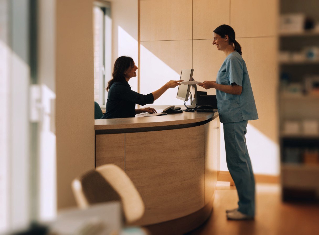 Dental practice manager and dentist reviewing paperwork at a practice reception desk during a change of ownership