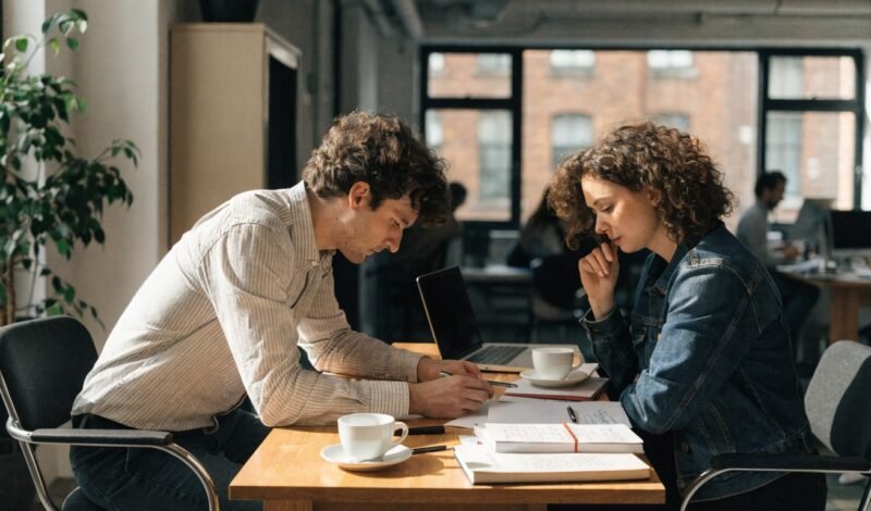 Two startup founders reviewing legal paperwork together at a desk in a London co-working office