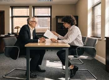 Two people reviewing a dental partnership agreement document at a solicitor's office table