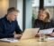 business owners and a solicitor reviewing financial statements across a meeting room table while negotiating an earn out Business owners and a solicitor reviewing financial statements across a meeting room table while negotiating an earn-out