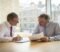 Two business owners reviewing an exclusivity agreement across a table in a London meeting room