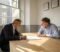 Two business owners reviewing a printed document across a table in a London meeting room