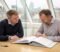 Two business owners reviewing acquisition documents together across a meeting table in a London office