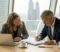 A solicitor and a business owner reviewing a bound share purchase agreement together in a London boardroom