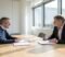 Two business owners discussing a company sale across a meeting table in a London solicitors' office