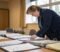 a small business owner working through files of company paperwork in an office meeting room while preparing her business for sale A small business owner working through files of company paperwork in an office meeting room while preparing her business for sale